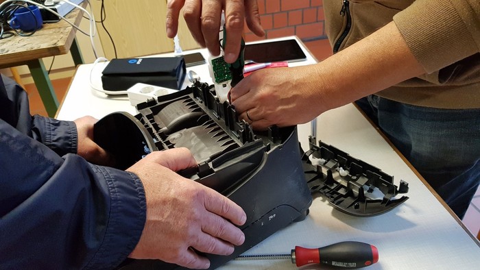 Hände die einen defekten Staubsauger reparieren.