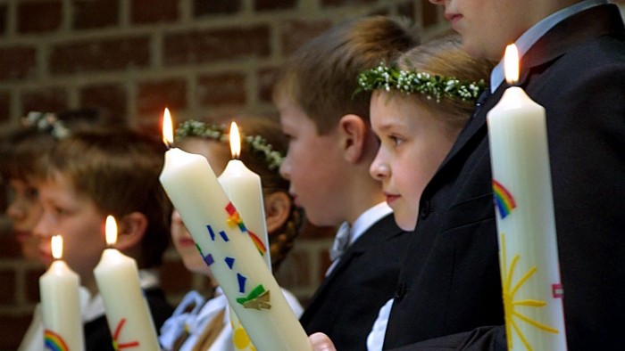 Kinder, die in einer Reihe brennende Kerzen halten