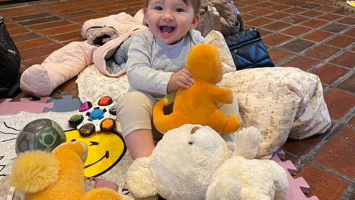 Barn sidder med bamser på legetæppe.