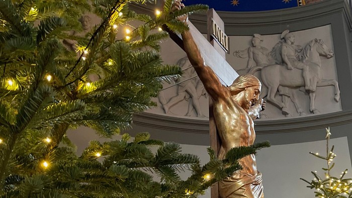 En juletree med lys og en guldstatue af Jesus på korset.