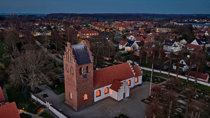 En lille by med en central kirke med tårn og røde tag.
