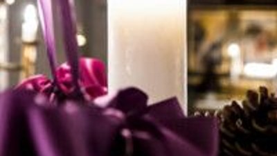 En lysende lyse med rød bånd og grønne blader på en mørk underlag