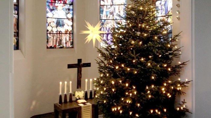 Weihnachtsbaum in der Kirche mit Kerzen und Kreuz