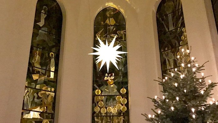 Weihnachtsbaum vor Kirchenfenstern mit Sternenlicht
