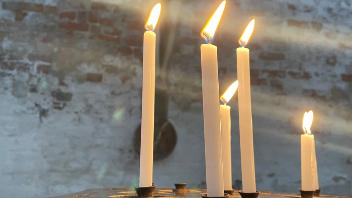 Kerzenschein vor Kreuzigungsbild in Kirche