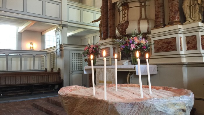 In der Kirche stehen Kerzen und Blumen auf einem Tisch.