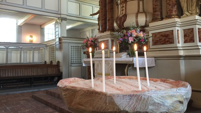 In der Kirche stehen Kerzen und Blumen auf einem Tisch.