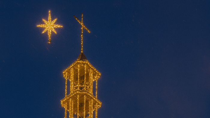 Silhouette eines Schneemanns vor hell erleuchteten Weihnachtsdekorationen.