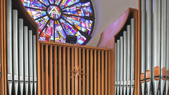Ein Kirchenorgel vor einem bunten Buntglasfenster