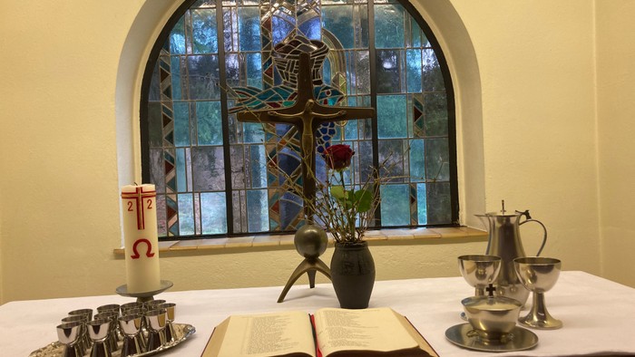 Ein Tisch mit Kerzen, Buch und Teekanne vor einem buntglasfenster
