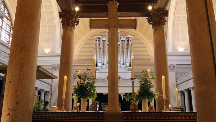 Großzügige Kirchenhalle mit Säulen, Orgel und Blumenarrangements