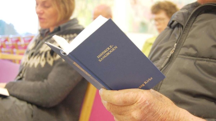 En hånd holder et blå håndbog med guldskrift.