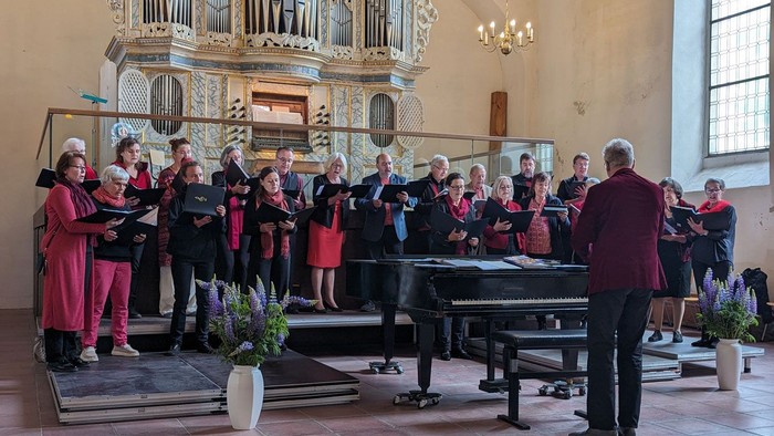 Ein Chor in roter und schwarzer Kleidung singt in der Kirche in Bad Belzig.