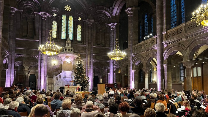 Une église avec une grande foule et un sapin de Noël.