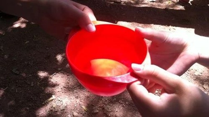 Kinder spielen mit einer roten Schale im Freien.
