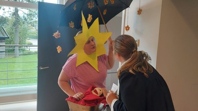 To personer pynter en papfigur med en sol og en paraply og laver et sjovt kreative projekt indendørs.