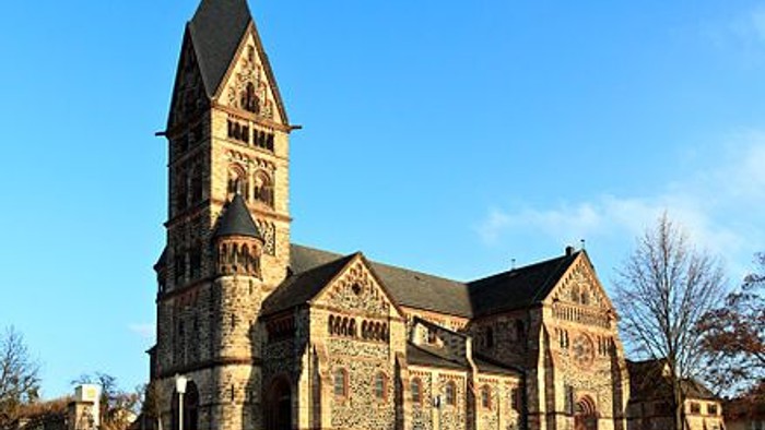 Historische Steinkirche mit filigraner gotischer Architektur und einem hohen, spitzen Glockenturm.