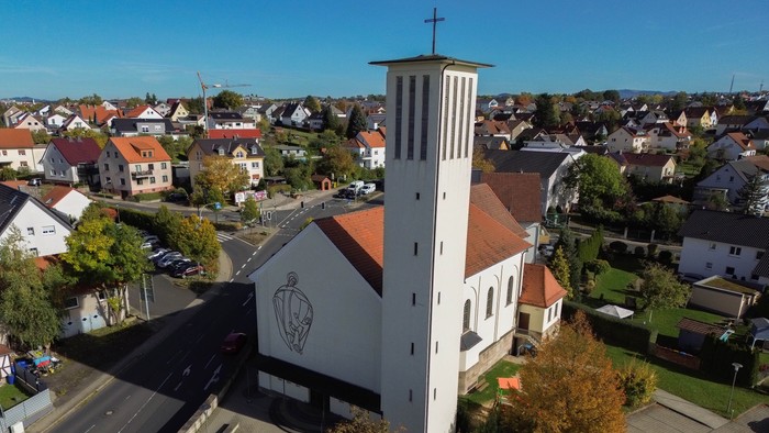 Weiße Kirche mit hohem Turm in Wohngebiet