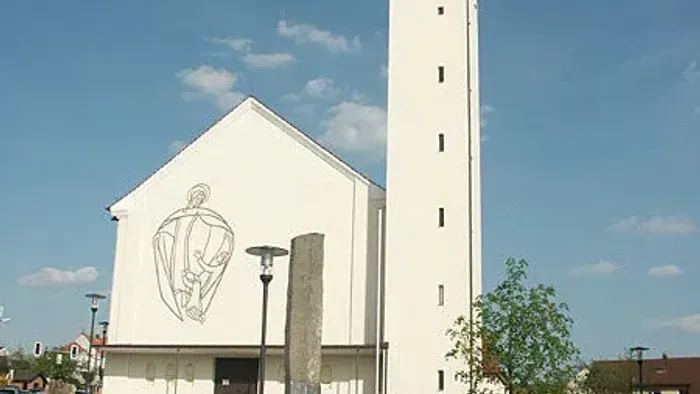Weiße Kirche mit hohem Turm und Person auf Platz