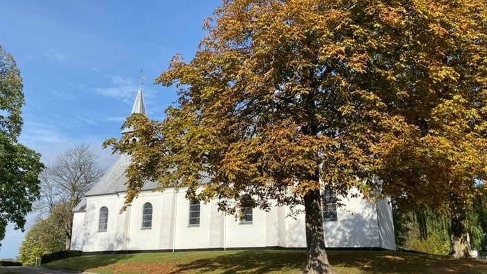 Hvid kirke og kastanjetræ med efterårsblade.