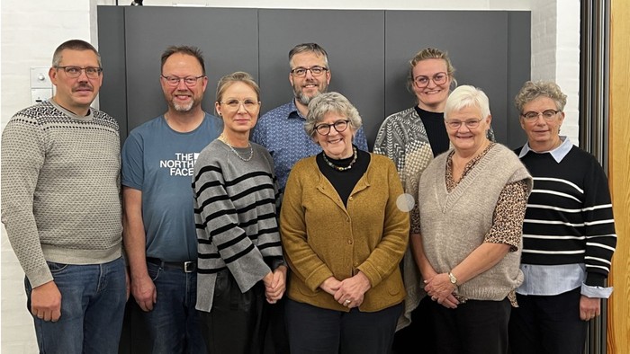 En gruppe af ni personer står sammen for en fotograf.