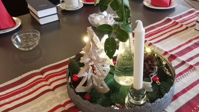 Billedet viser dækkede juleborde med en lille anretning med en rose lys og juletræ