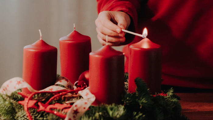 Person zündet Kerzen an Weihnachtsdekoration