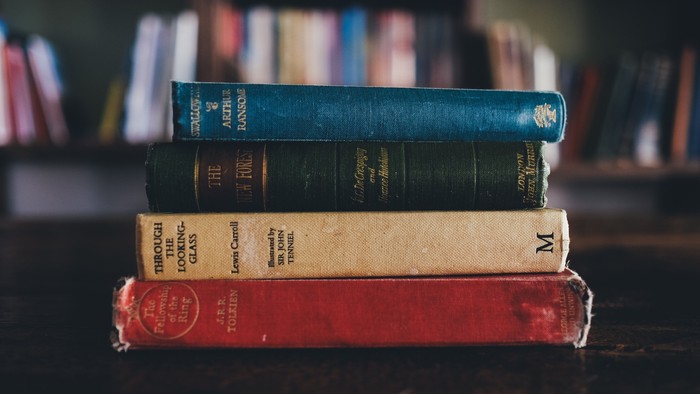 Tre bøger stakket op på hinanden på en skrivebord