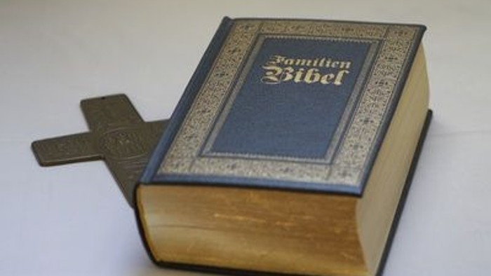 Ein blau gebundener Bibel liegt auf einem weißen Hintergrund.