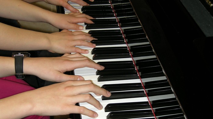 viele Hände auf der Klaviertastatur