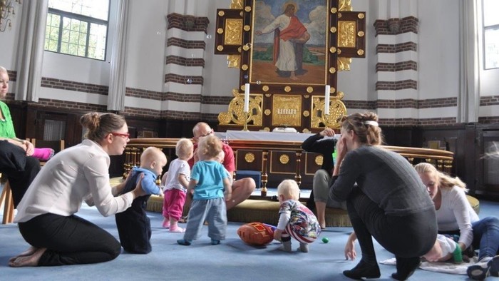 En gruppe voksne og børn i kirke foran altertavle