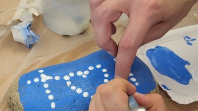 Børn maler sten med blå og hvide point