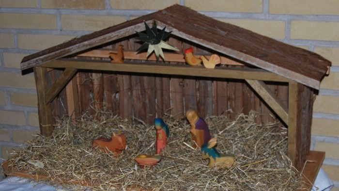 En lille nativity scene med figurer og hest i en skure.