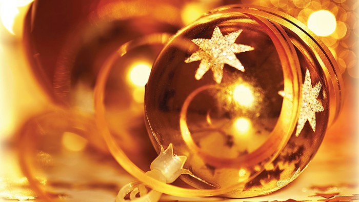Gulde juledekorationskugle med stjerner og lys.