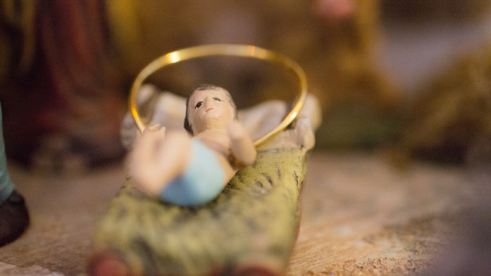 En lille figur af en baby i en køje med et guldrem.