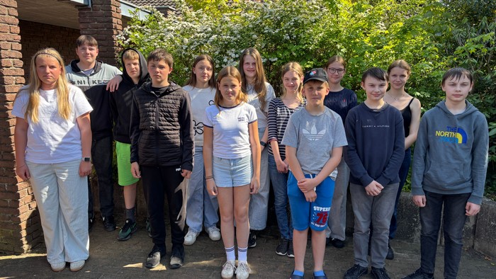 Eine Gruppe von Jugendlichen steht vor einem Haus und posiert für ein Foto.