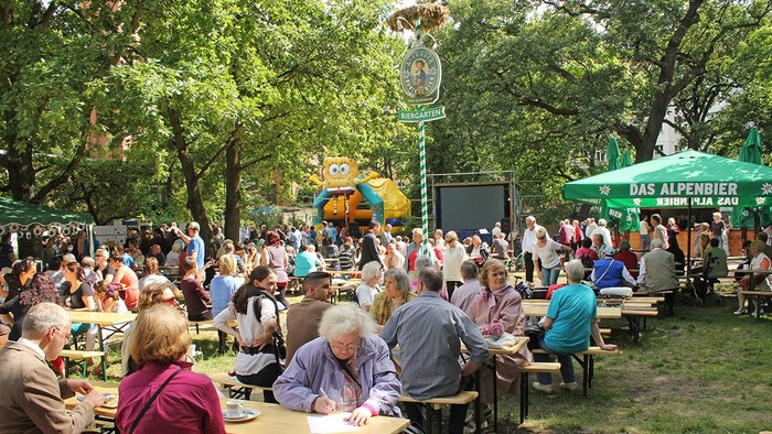 Ein großer Biergarten mit vielen Menschen, die an Tischen sitzen und trinken.