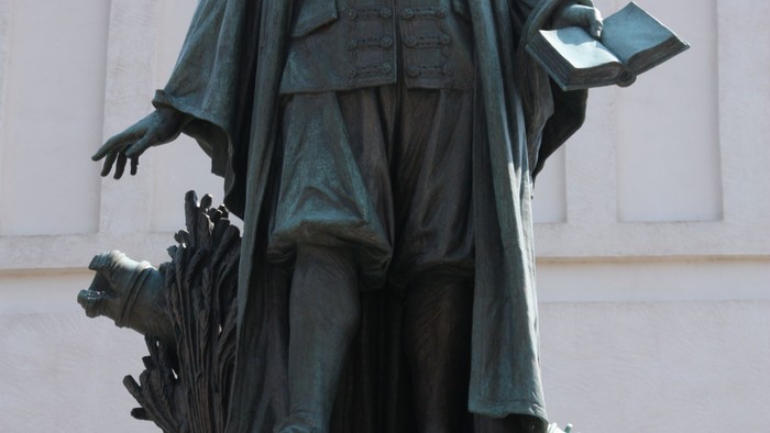 Die Bronzestatue eines Mannes mit Buch und Federkiel.