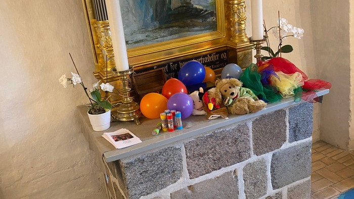 En hylle med billede, lysestage, blomster og diverse dekorationer