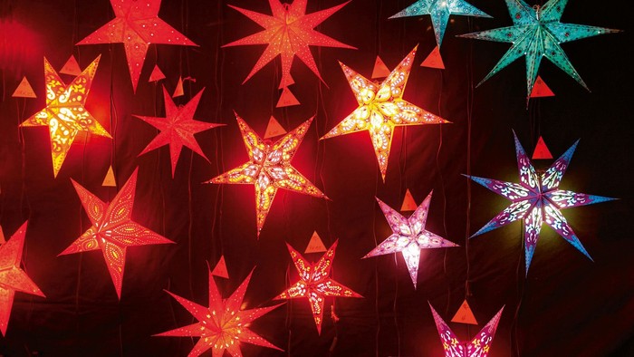 Leuchtende Sterne in verschiedenen Farben hängen im Dunkeln