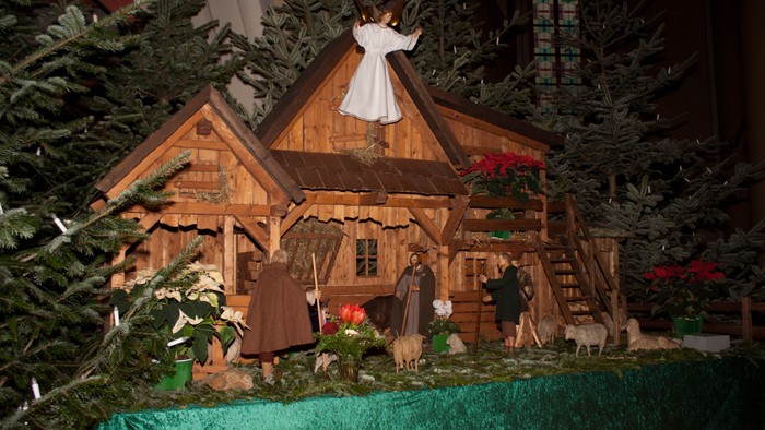 Ein hölzernes Weihnachtshaus mit Figuren und Tannenbäumen