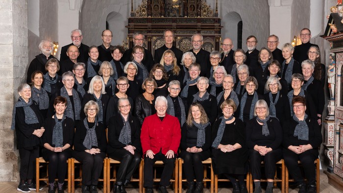 En stor korgruppe poserer i kirke med alter bagud.