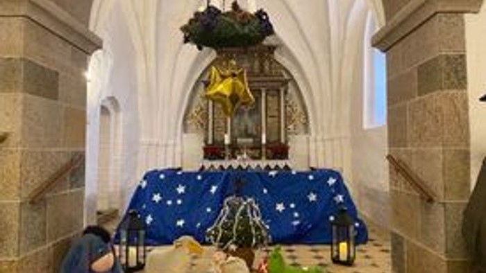 En altertavle i en kirke med blå tæpper og forskellige dyr og figurer på den.