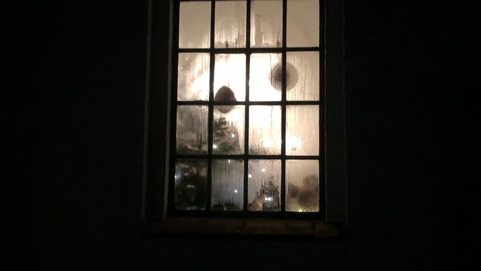 Et vindue med bueformet øverste del og en svag lysstråle.