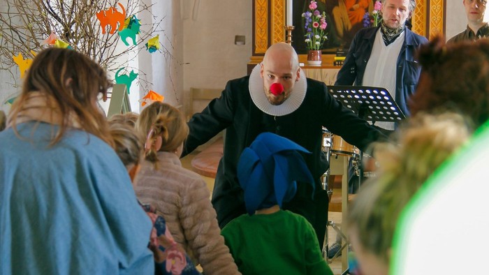 Præst med klovnenæse der taler til børn i kirken