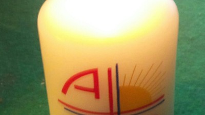 Eine brennende Kerze mit den griechischen Buchstaben Alpha und Omega und einem Sonnensymbol dazwischen.