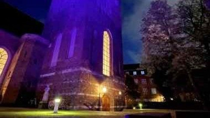 Ein beleuchtetes Kirchengebäude bei Nacht mit farbigem Licht.