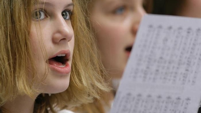 Zwei Mädchen singen aus einem Notenblatt.
