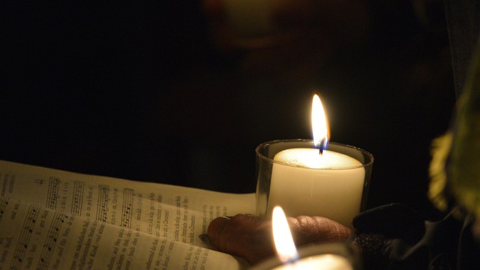 Drei brennende Kerzen auf einem Buch im Dunkeln