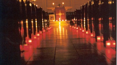 Kirchliche Innenansicht mit zahlreichen brennenden Kerzen in roten Haltern